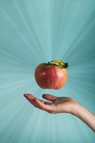 Bildretusch av ett svävande äpple från en hand.